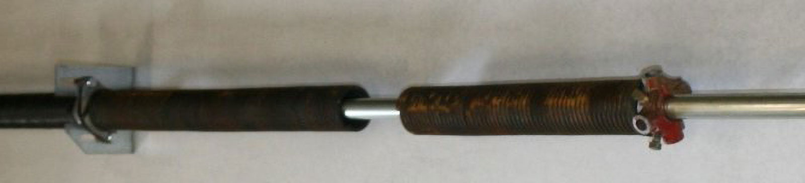 Close-up view of a snapped torsion spring mounted above a sectional garage door in Folsom, California.