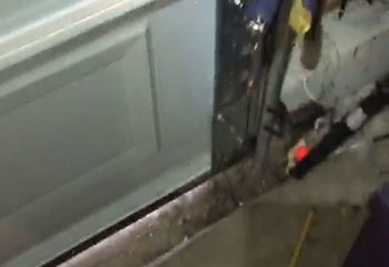 Technician adjusting safety sensor mounting and wiring on the lower garage door track in Citrus Heights, California.